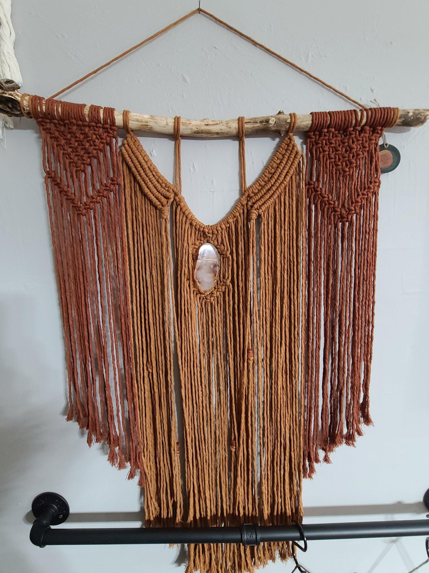 large red and orange macramé wall hanging with agate on a stick